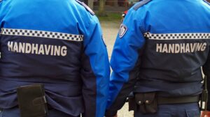 Twee Schiedamse handhavers op de rug gezien. Er staat in hoofdletters 'handhaving' op hun rug.
